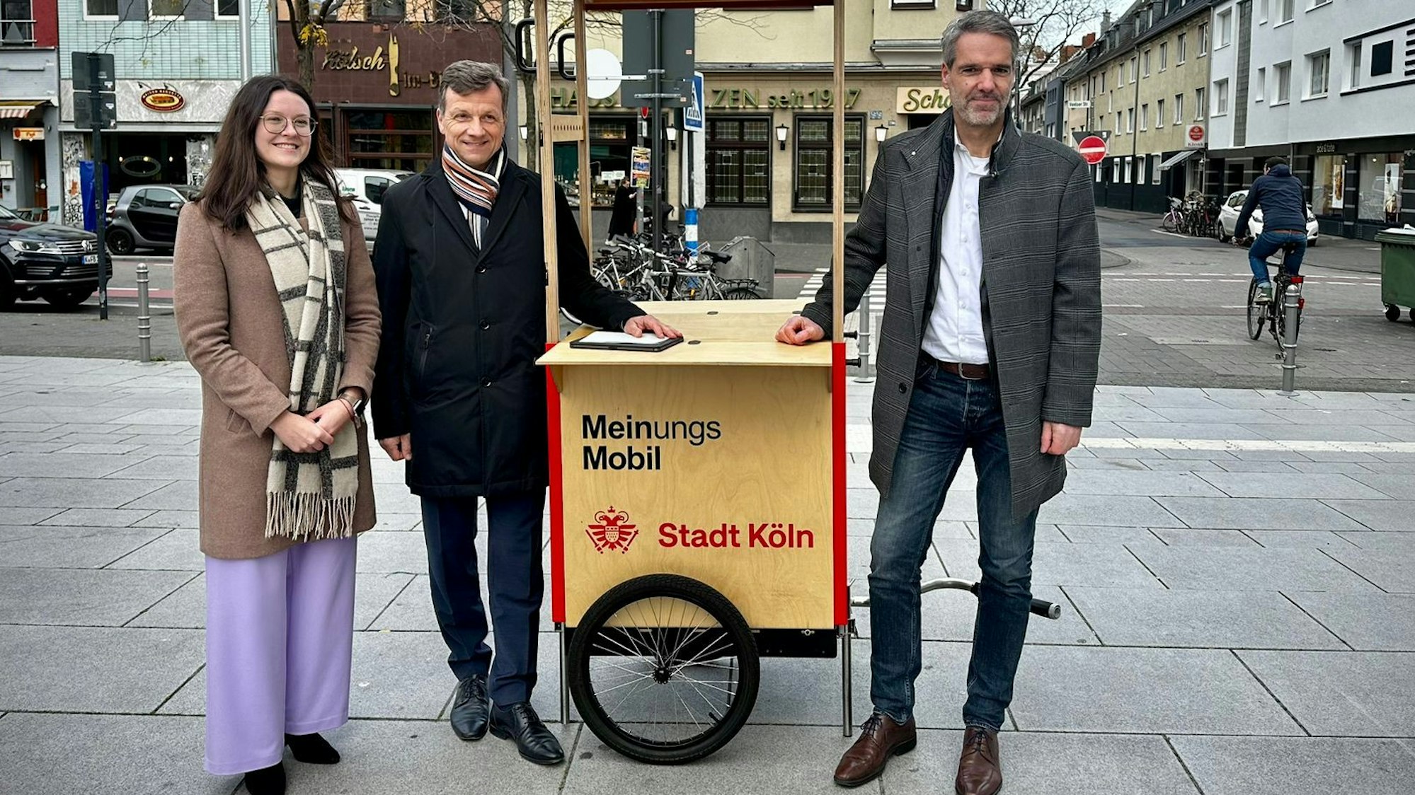 Katharina Pitko, Ascan Egerer und Christian Dörkes stehen mit dem Meinungsmobil der Stadt Köln an der Venloer Straße.