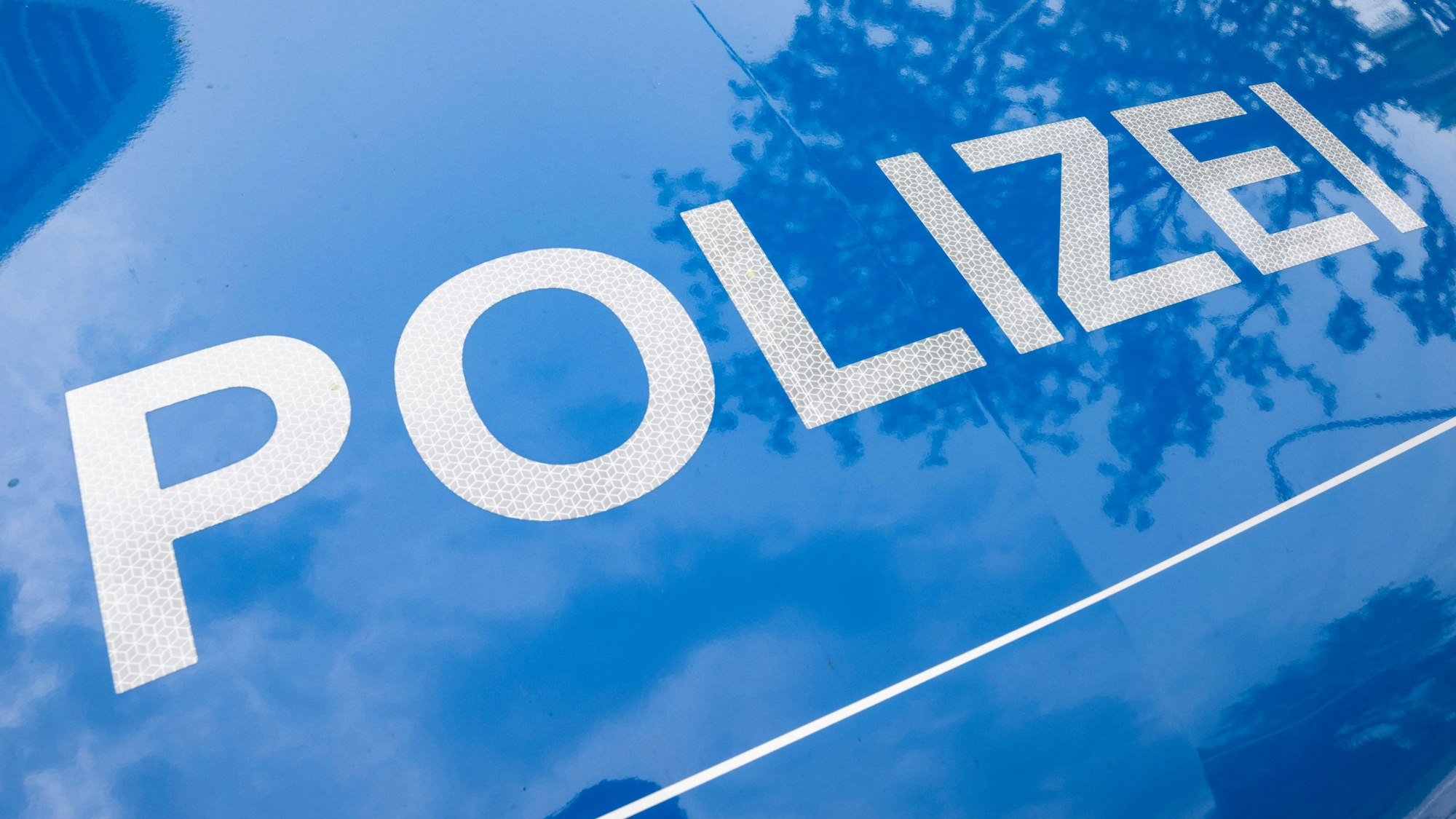 Der Schriftzug „Polizei“ ist auf einem Streifenwagen zu sehen.