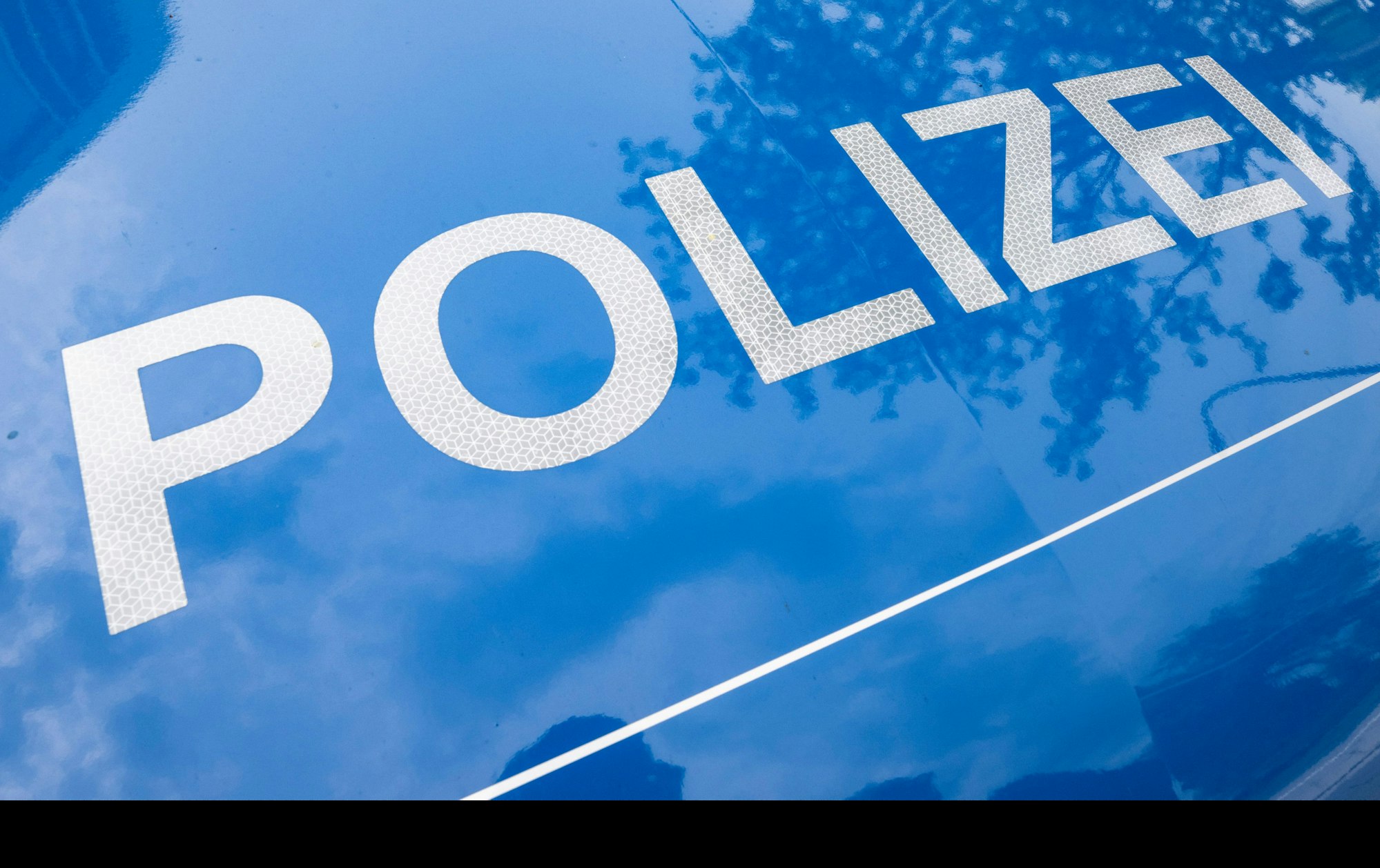 Der Schriftzug „Polizei“ ist auf einem Streifenwagen zu lesen.