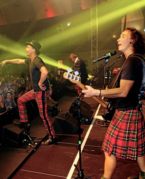 Die Band Brings steht bei einem Konzert in einer Halle auf der Bühne und singt mit dem Publikum.