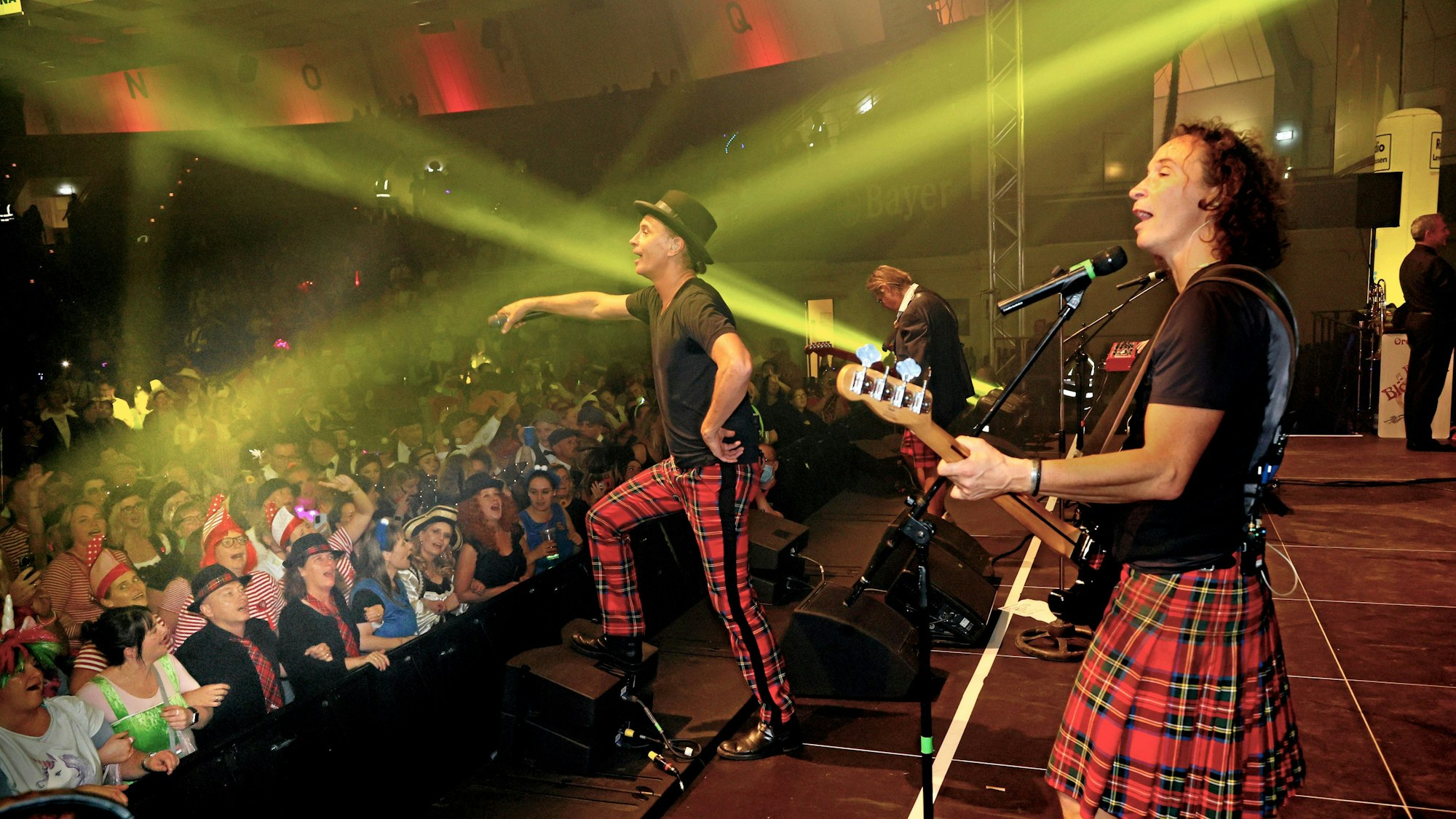 Die Band Brings steht bei einem Konzert in einer Halle auf der Bühne und singt mit dem Publikum.