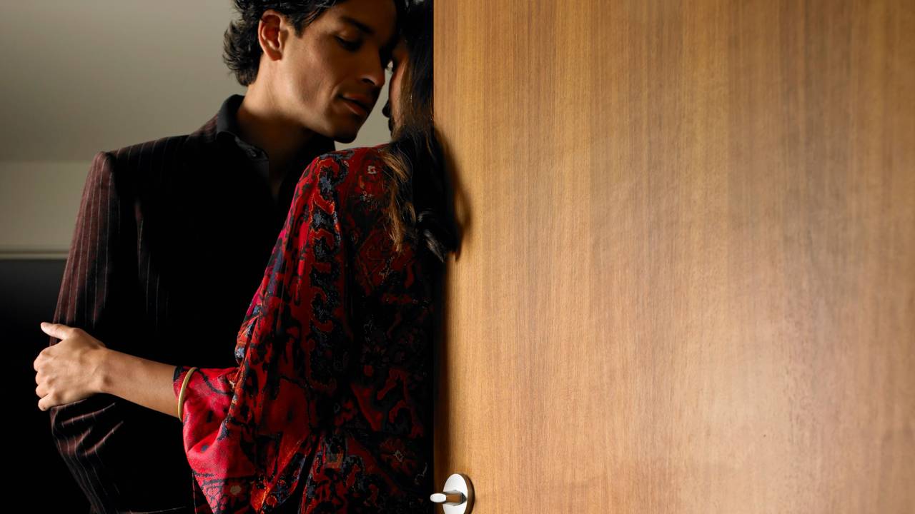 Das undatierte Symbolfoto zeigt einen Mann und eine Frau in eindeutig erotischer Absicht vor der Tür eines Hotelzimmers samt "Bitte nicht stören"-Schild.