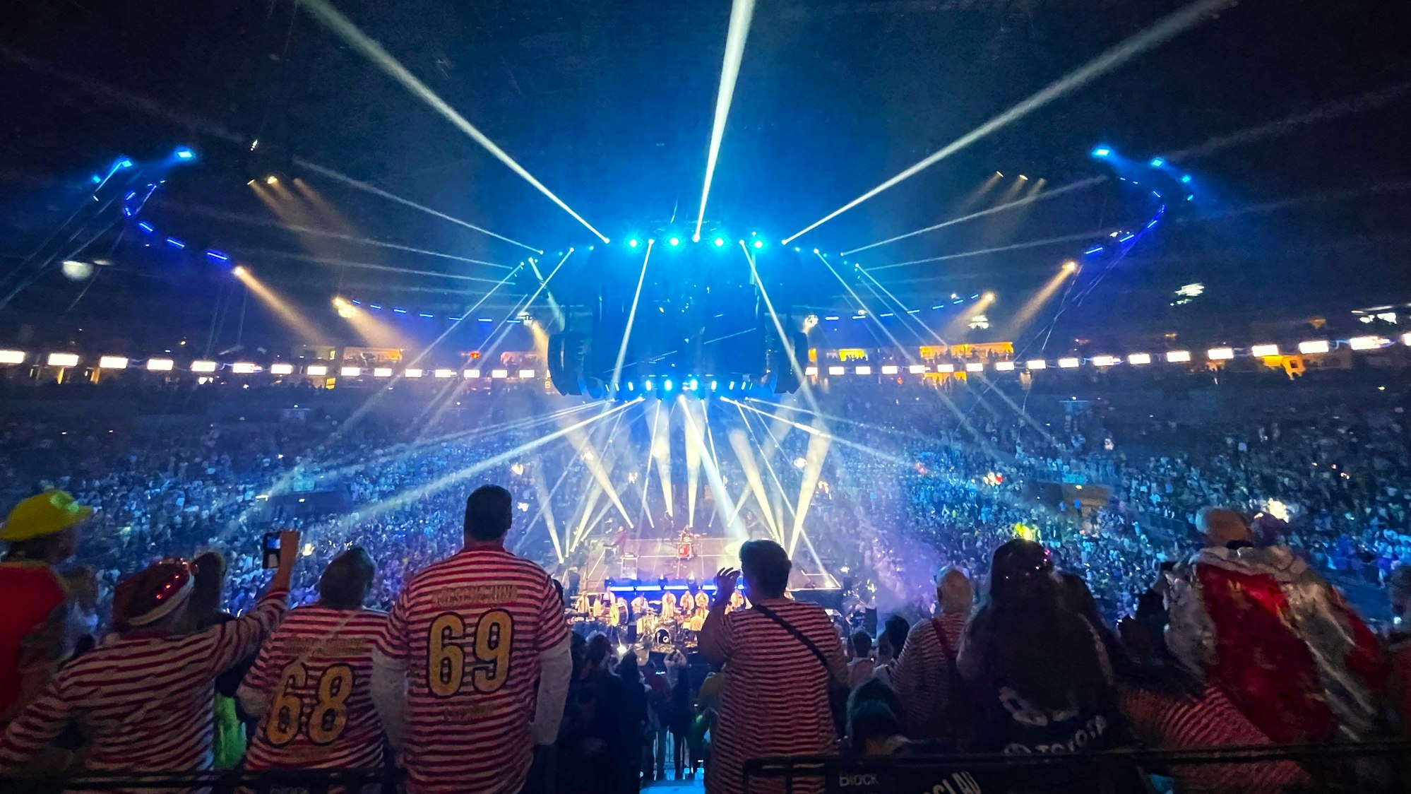 Menschen in Kostümen feiern in der vollen Lanxess-Arena in Köln den Start in die Karnevalssession.
