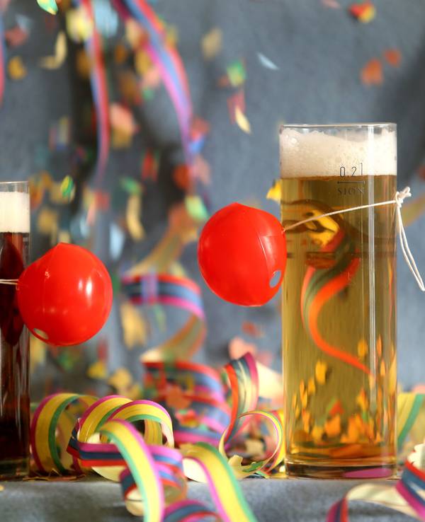 Hier zu sehen: Ein Altbier und ein Kölsch stehen, mit roten Pappnasen geschmückt, auf einem bunt dekorierten Tisch.