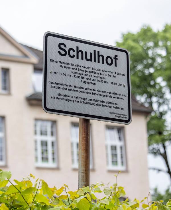 Regeln zum Aufenthalt auf dem Schulhof einer Grundschule sind vor dem Schulgebäude auf einem Schild zu lesen. Unter Ausschluss der Öffentlichkeit hat in Bochum am Freitag der Prozess um den gewaltsamen Tod einer 19-Jährigen begonnen.