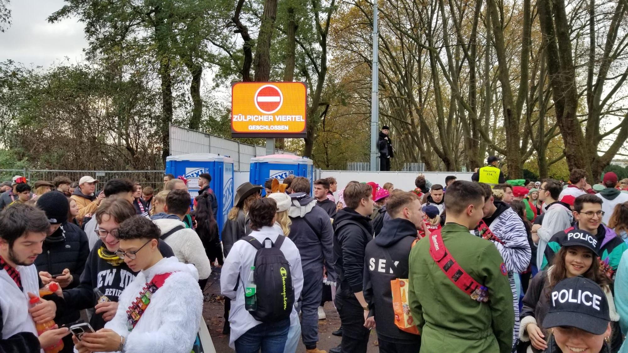 Viele Menschen wollen an der Uni-Mensa in Köln auf die Zülpicher Straße, aber die Eingänge sind dicht.