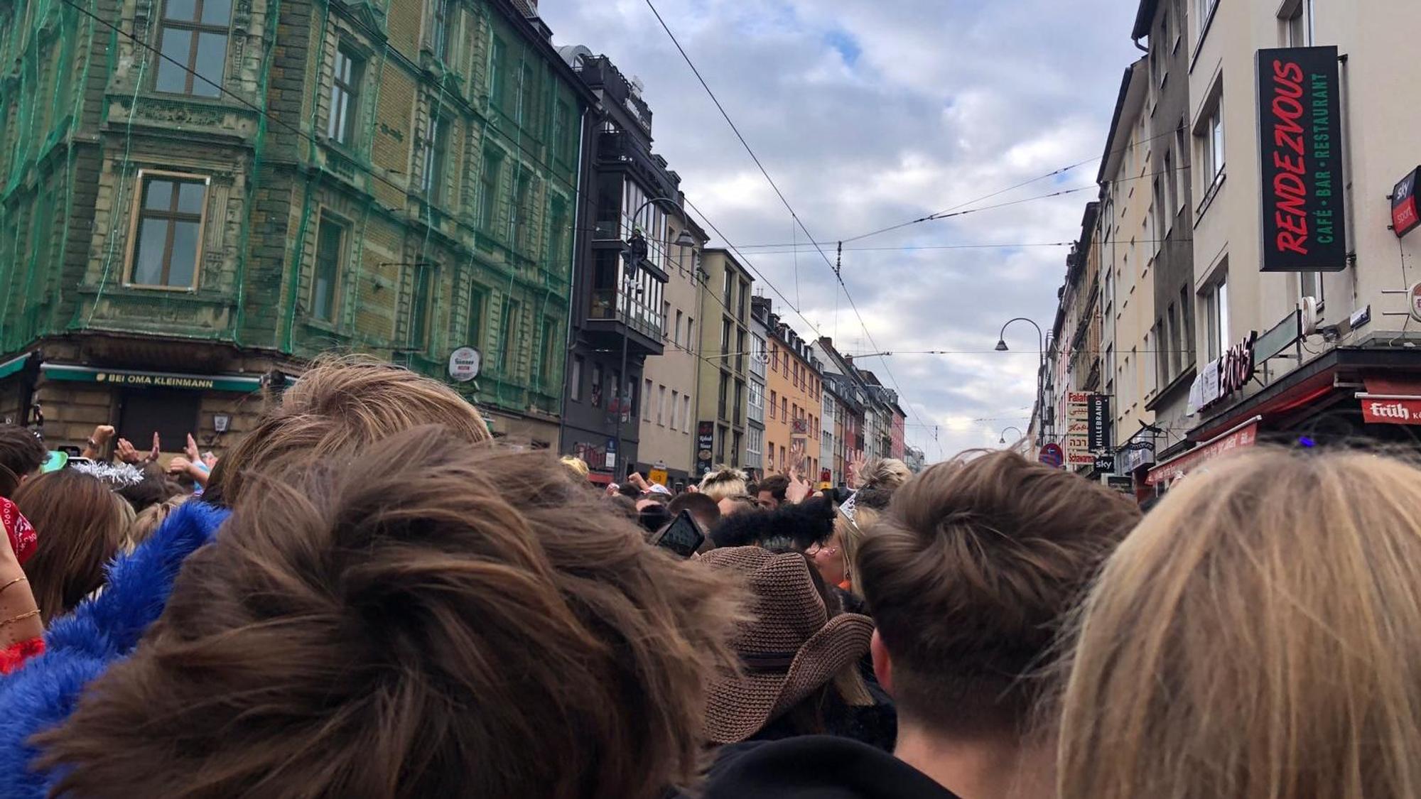 Blick von unten auf die Zülpicher Straße, wo ein Feiernder auf eine Straßenlaterne klettert.