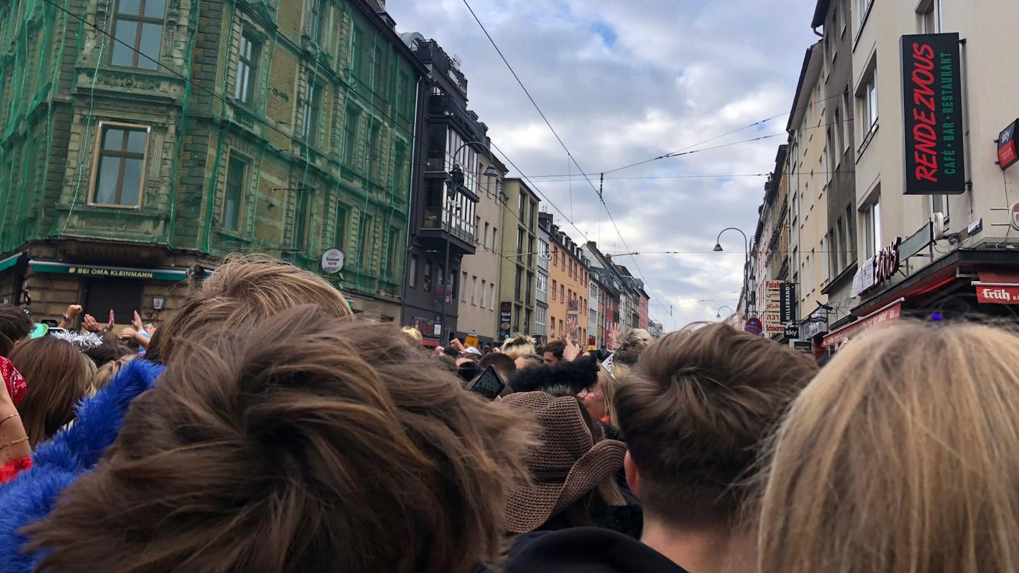 Blick von unten auf die Zülpicher Straße, wo ein Feiernder auf eine Straßenlaterne klettert.