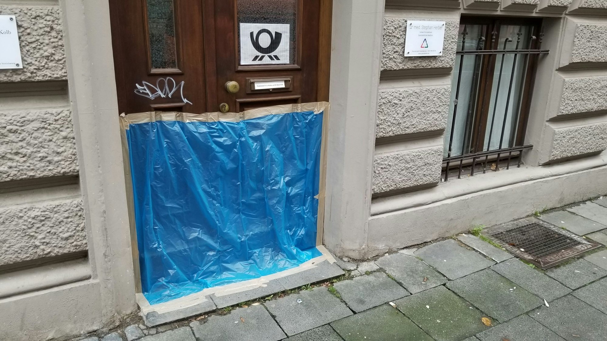 Blaue Plane verdeckt einen Hauseingang.