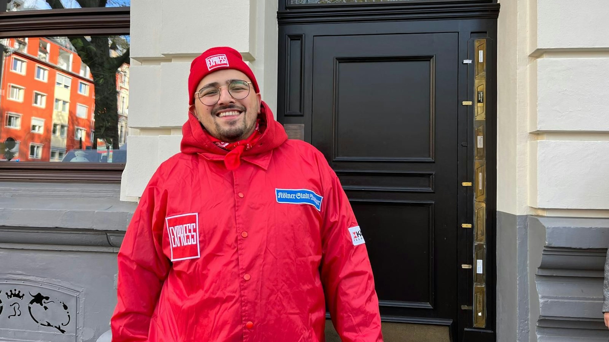 Arif Baynaz lächelt in rotem EXPRESS-Kostüm in die Kamera.