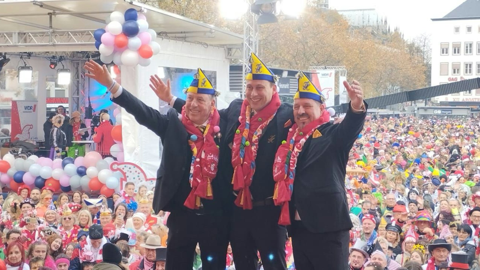 Das neue Dreigestirn steht vor der feiernden Menge am Heumarkt in Köln.