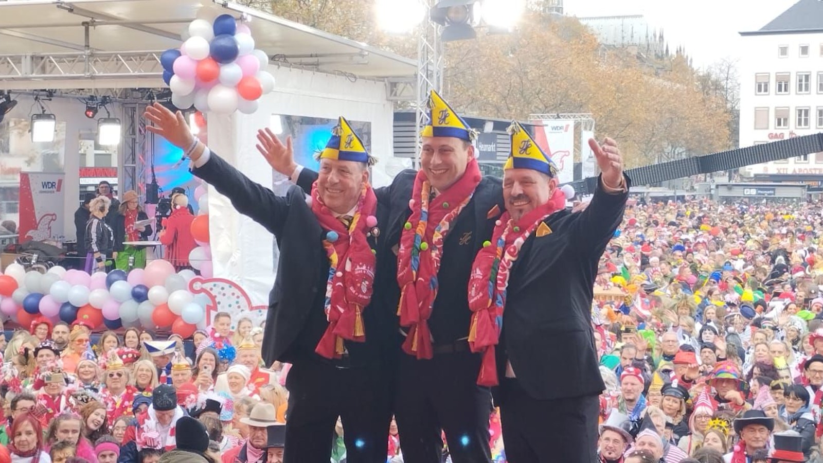 Das neue Dreigestirn steht vor der feiernden Menge am Heumarkt in Köln.