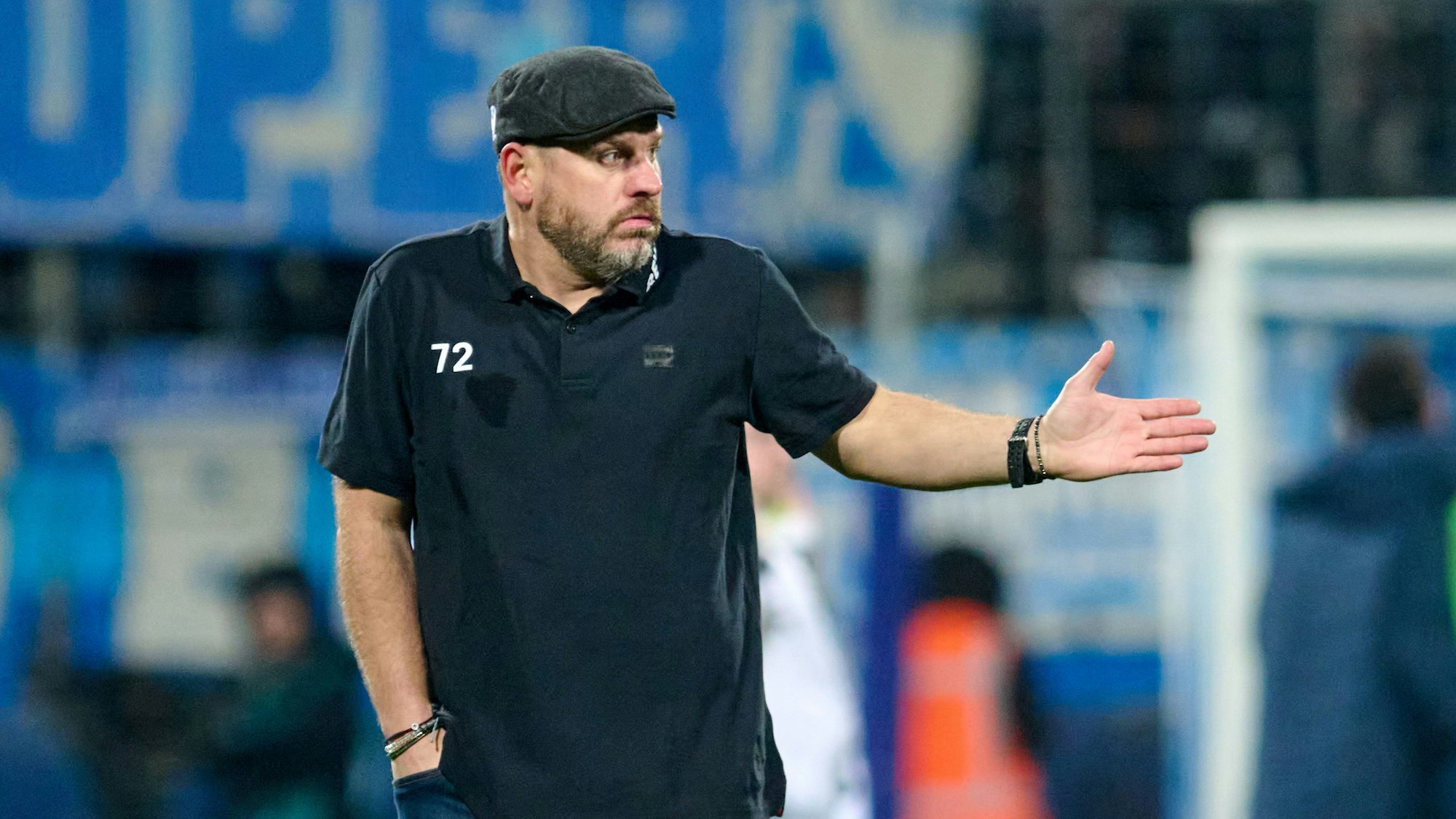 Steffen Baumgart in schwarzem T-Shirt und Schiebermütze an der Seitenlinie.