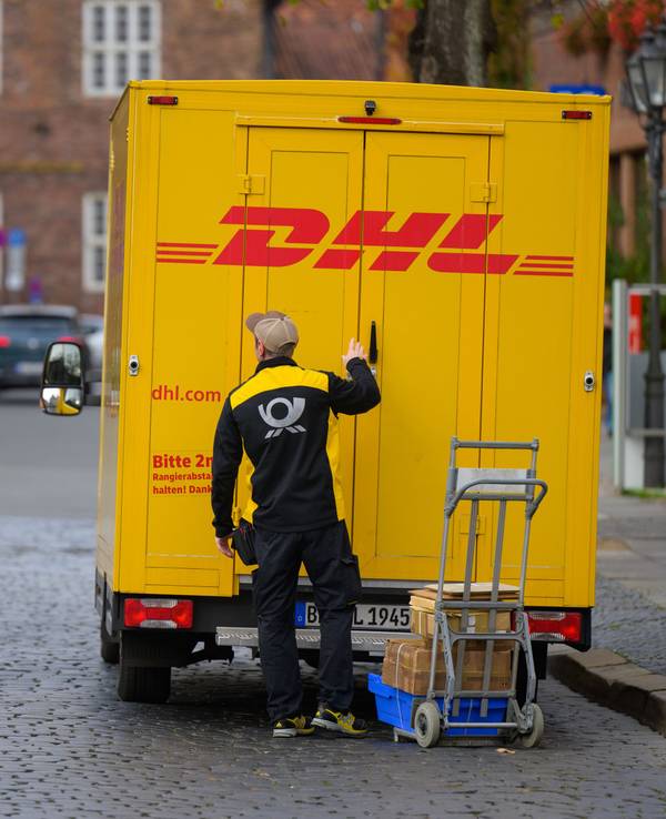 Ein Zusteller entlädt ein Fahrzeug von DHL in der Innenstadt.