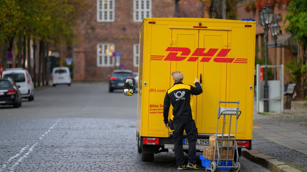 Ein Zusteller entlädt ein Fahrzeug von DHL in der Innenstadt.