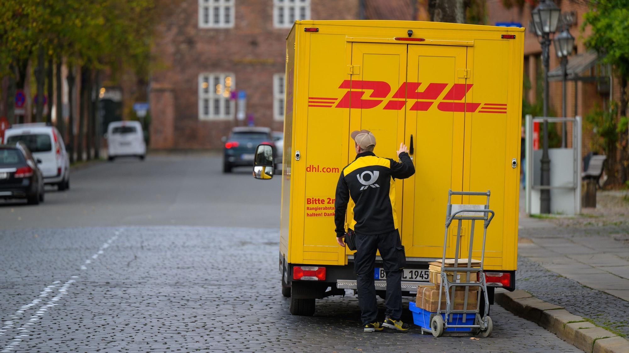 Ein Zusteller entlädt ein Fahrzeug von DHL in der Innenstadt.