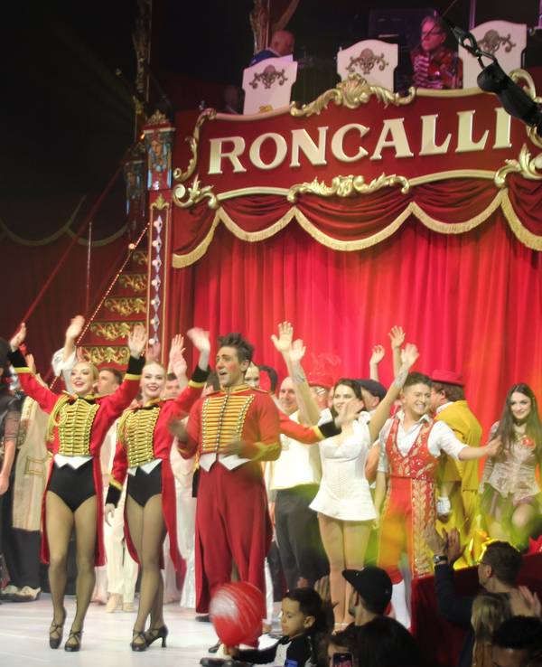 Artistinnen und Artisten stehen in der Manege des Circus Roncalli und winken.