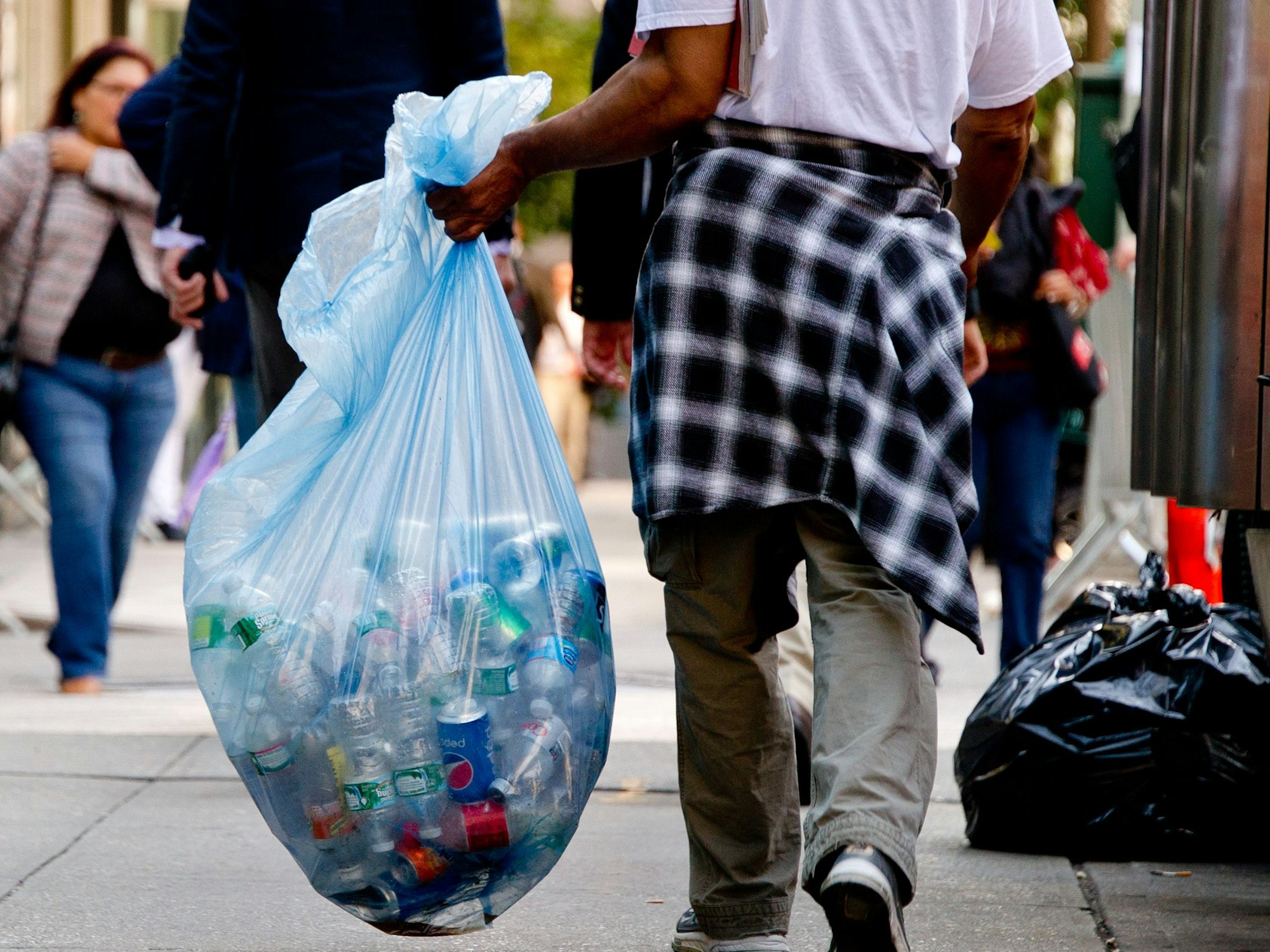 Ein Mann trägt in New York (USA) einen Sack mit Pfandflaschen.