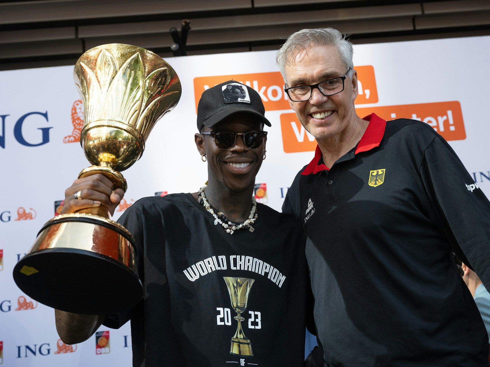 Dennis Schröder (l), Kapitän der Basketball-Nationalmannschaft, und Bundestrainer Gordon Herbert jubeln mit dem WM-Pokal.