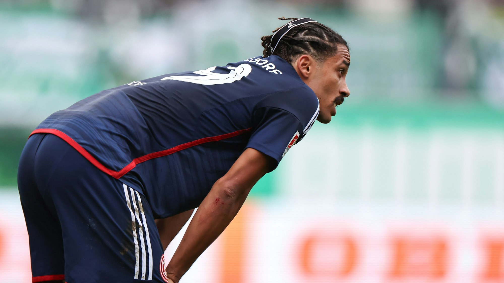 Emmanuel Iyoha stützt sich nach der Niederlage bei Greuther Fürth enttäuscht auf seinen Oberschenkeln ab.