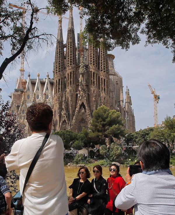 Touristen fotografieren in Barcelona (Spanien) die Basilika Sagrada Família.