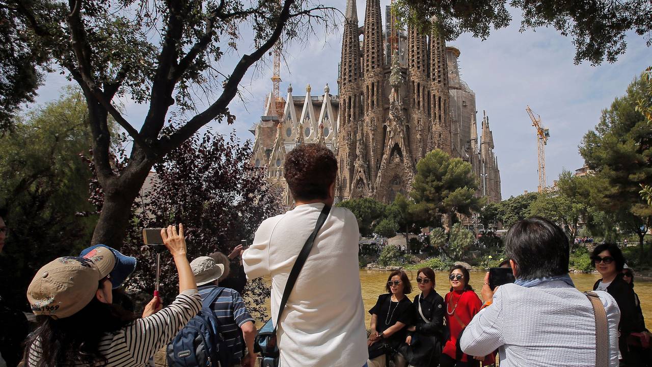 Touristen fotografieren in Barcelona (Spanien) die Basilika Sagrada Família.