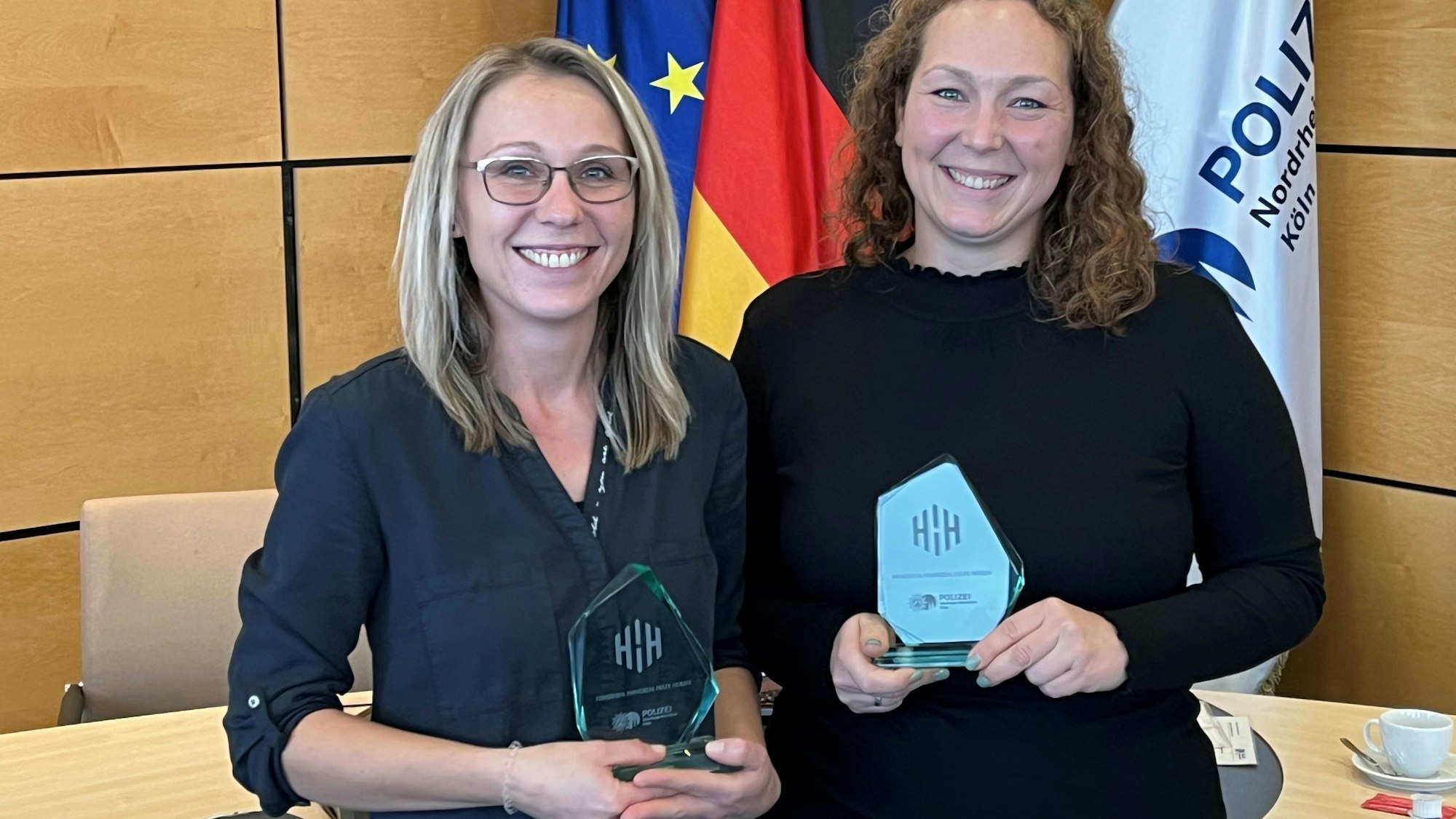 Zwei Frauen halten gläserne Auszeichnungen in Händen.