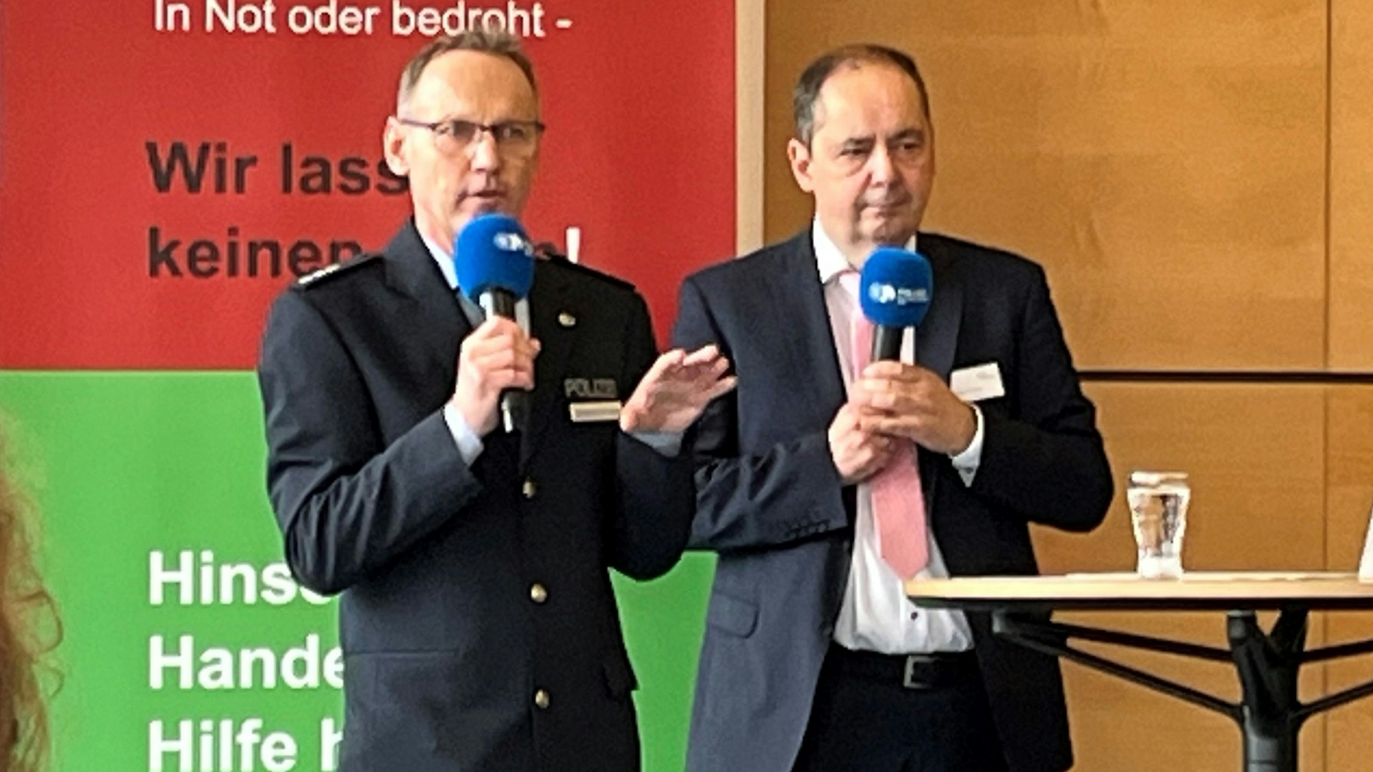 Zwei Männer mit jeweils einem Mikro stehen nebeneinander.