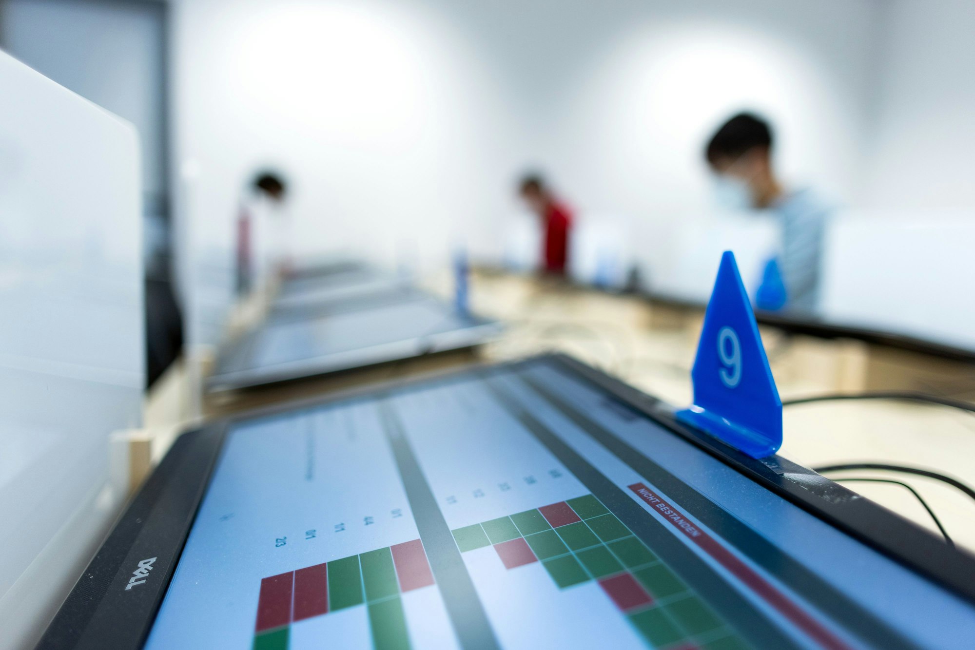 „Nicht bestanden“ steht auf einem Monitor bei der theoretischen Prüfung für den Führerschein beim TÜV, während im Hintergrund Prüflinge die Aufgaben absolvieren.