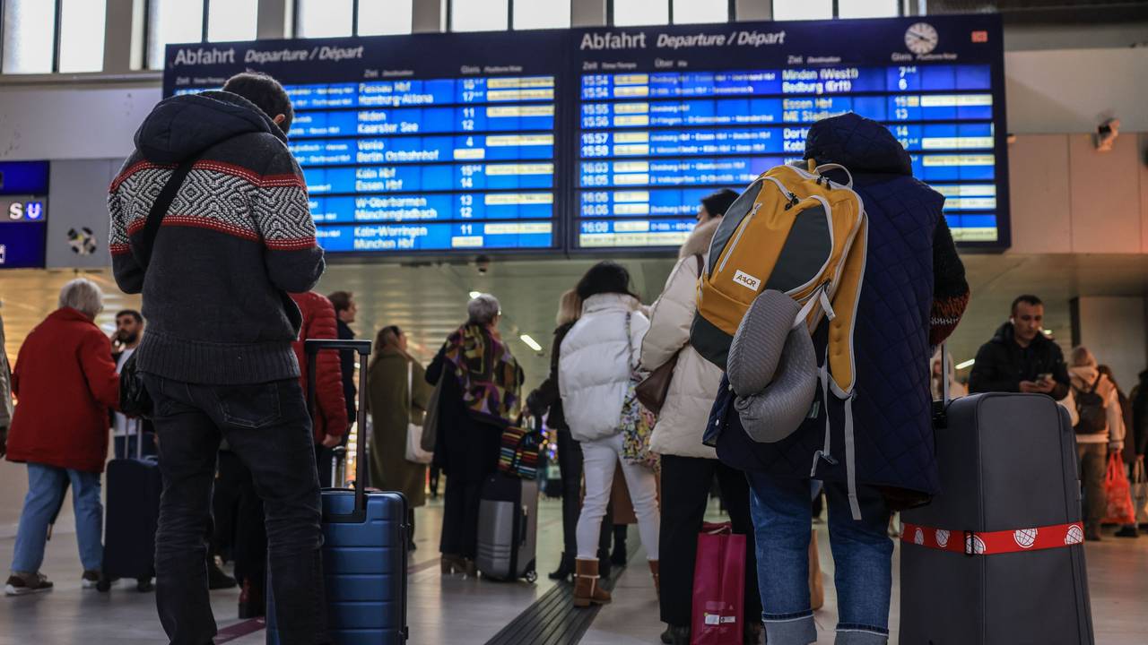 Reisende stehen im Hauptbahnhof Düsseldorf vor der Anzeigetafel.