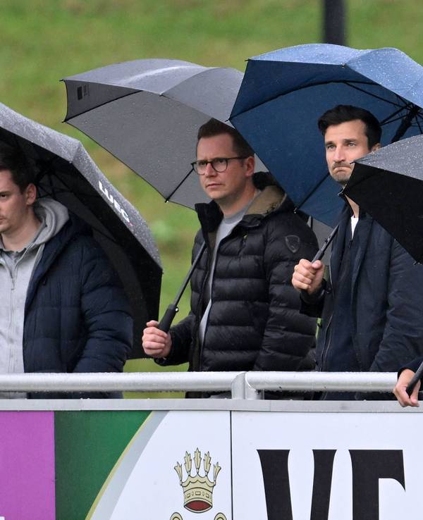Peter Knäbel steht neben Matthias Tillmann und André Hechelmann im Regen.