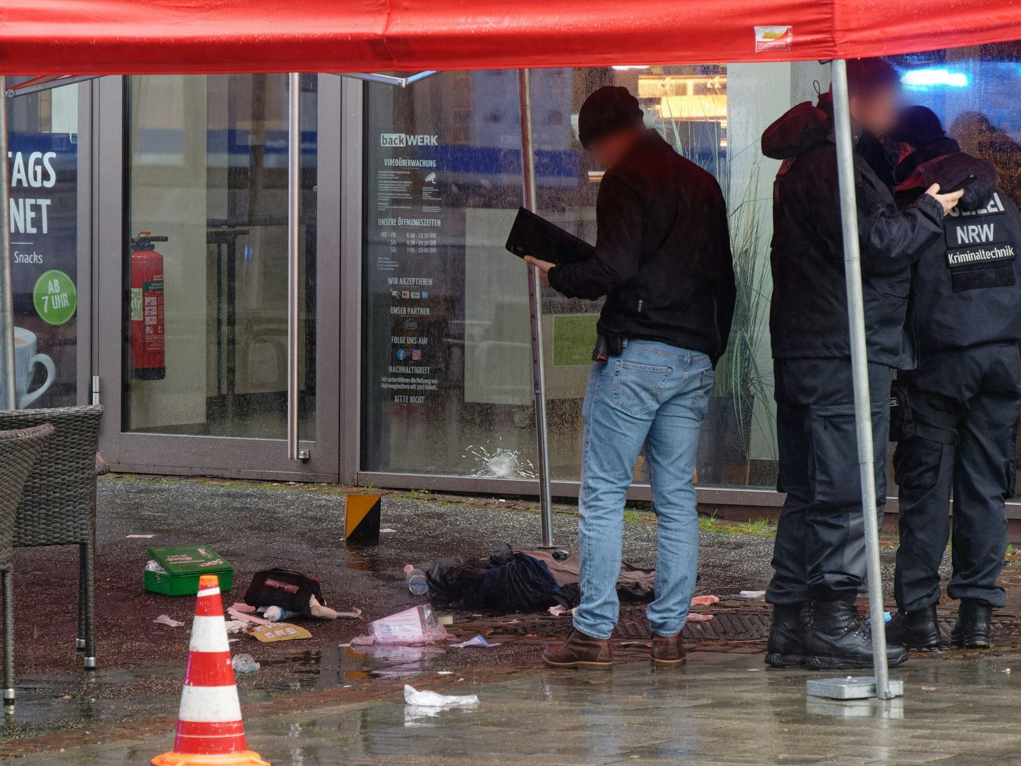 Polizeibeamte untersuchen unter einem Zeltdach den Tatort in der Innenstadt.