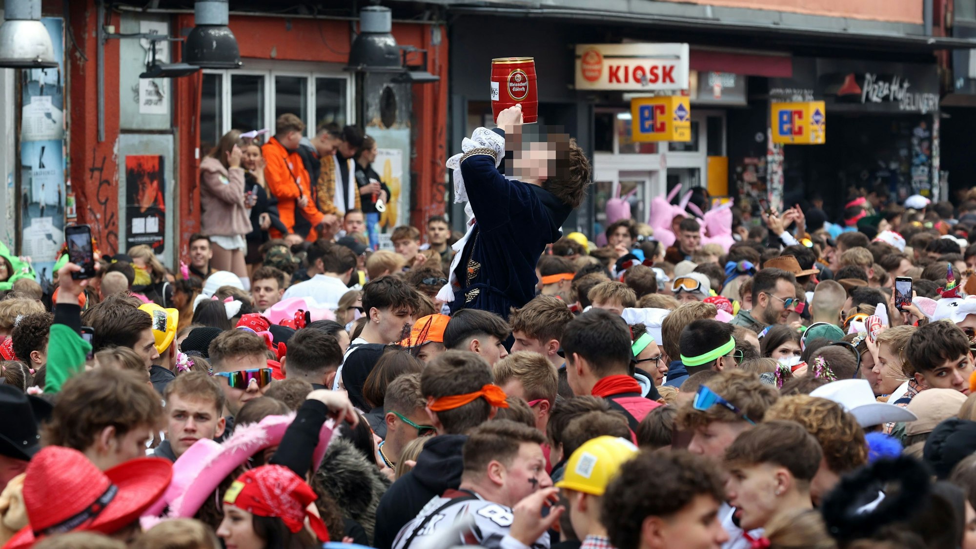 Ein Jugendlicher trinkt auf der Zülpicher Straße aus einem Fass Kölsch.