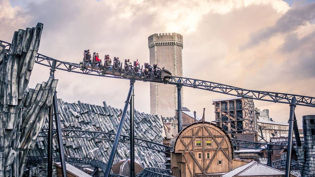 Blick von unten auf die Achterbahn Taron im Phantasialand. Im Hintergrund ist das Mystery Castle zu sehen.