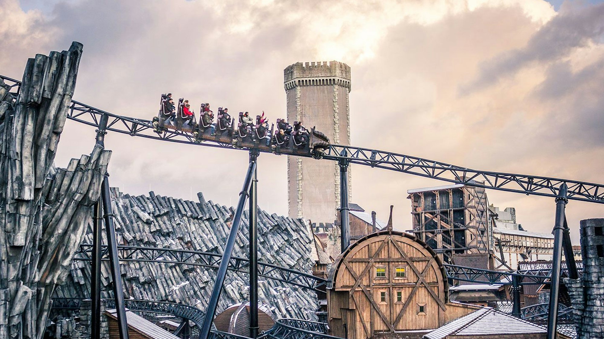 Blick von unten auf die Achterbahn Taron im Phantasialand. Im Hintergrund ist das Mystery Castle zu sehen.