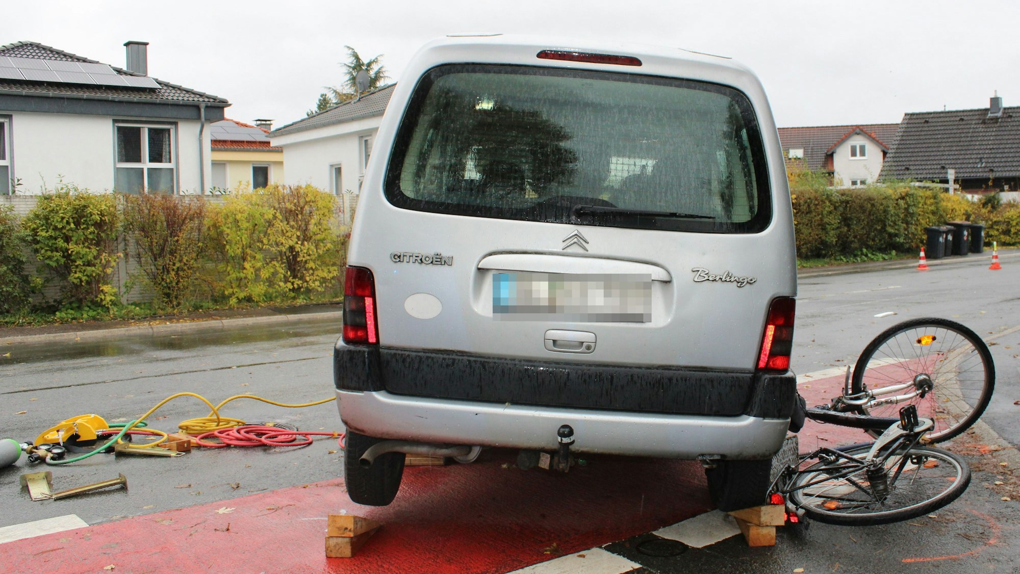 Foto einer Unfallszene. Unter einem Auto ist ein Fahrrad eingeklemmt.