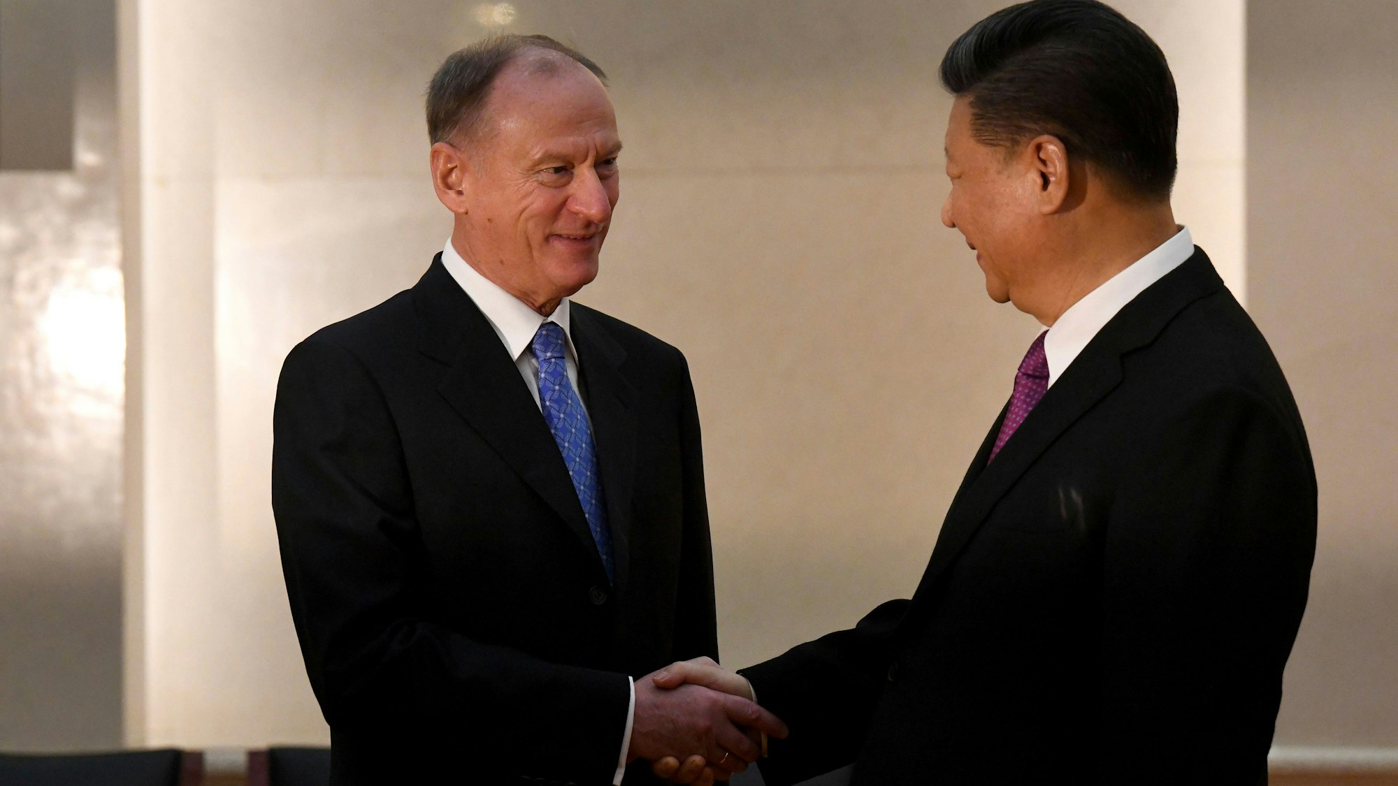 Xi Jingping (r.), Präsident von China, gibt Nikolai Patruschew die Hand.