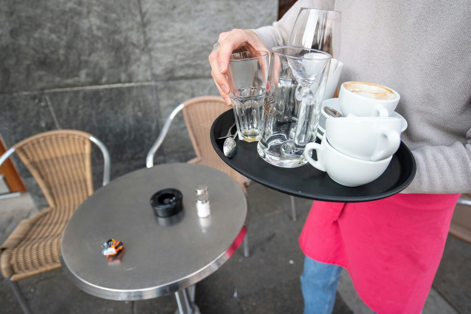 Ein Kellner räumt einen Tisch in einem Restaurant ab. Die Mehrwertsteuer auf Speisen in der Gastronomie wird zu Jahresbeginn wieder auf 19 Prozent angehoben.