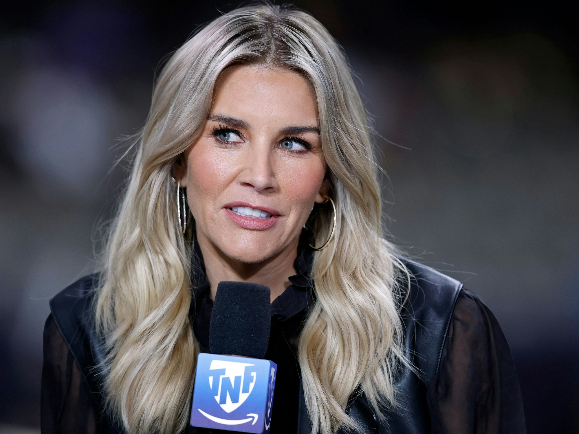 Moderatorin Charissa Thompson hält bei einer TV-Übertragung ein Mikrofon in der Hand.