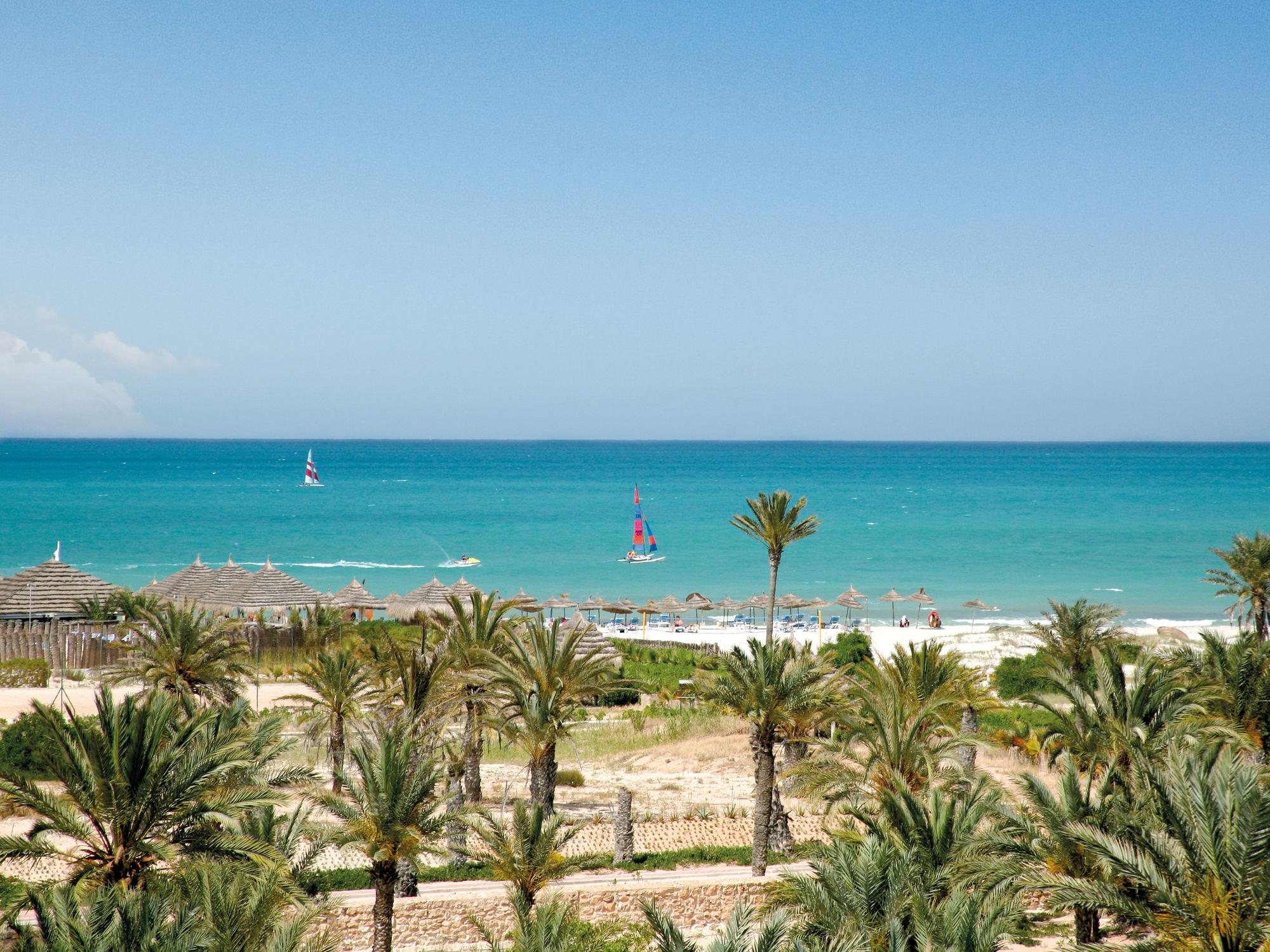 Das Foto zeigt einen Strand mit Palmen und türkisblauem Meer auf der Insel Djerba in Tunesien, aufgenommen im März 2016.