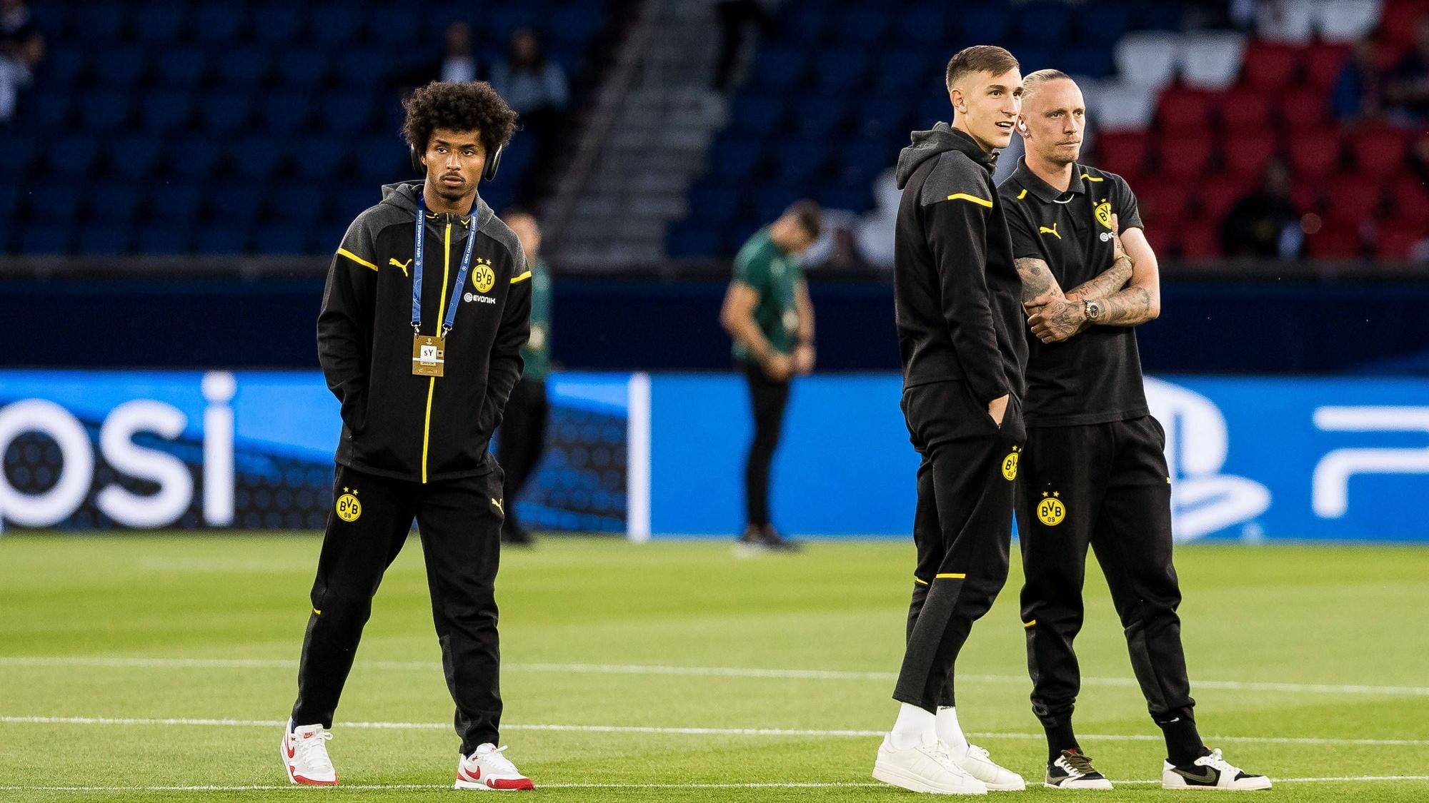 Karim Adeyemi, Nico Schlotterbeck und Marius Wolf vor einem Champions-League-Spiel auf dem Rasen.
