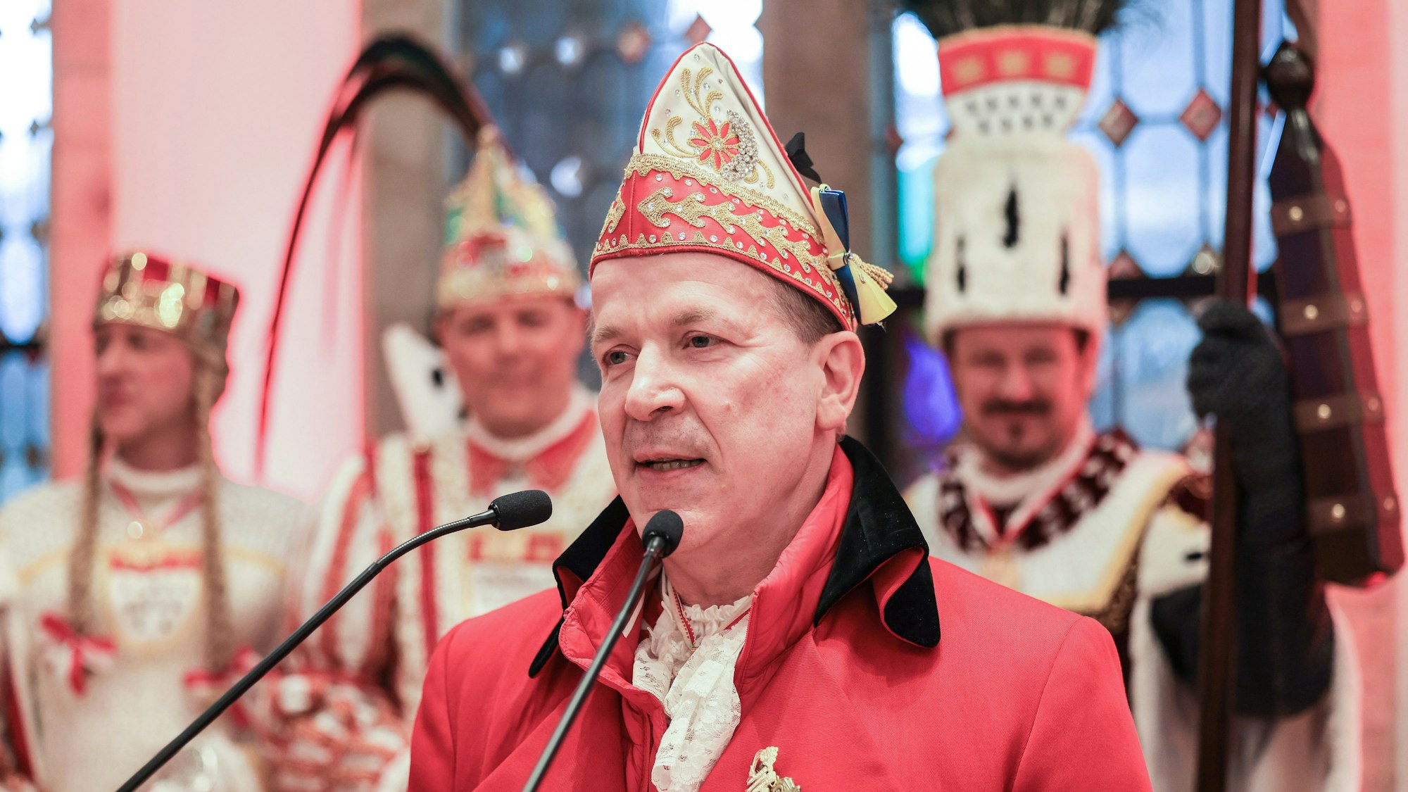 Christoph Kuckelkorn steht in Karnevalstracht vor einem Mikrofon und hält eine Rede.