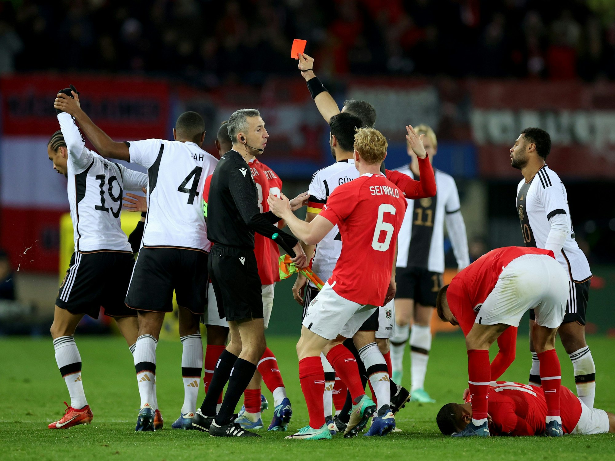 Deutschlands Leroy Sane (l) sieht die Rote Karte nach einer Tätlichkeit an Österreichs Phillipp Mwene (am Boden).
