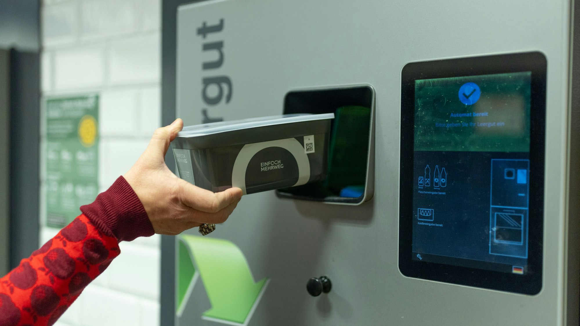 Eine Frau stellt ein Unverpackt-Gefäß in ein Rückgabegerät.