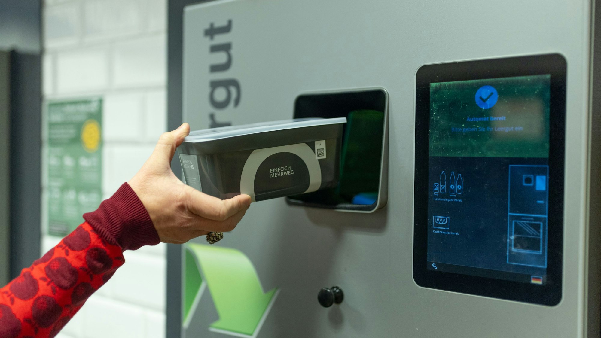 Eine Frau stellt ein Unverpackt-Gefäß in ein Rückgabegerät.