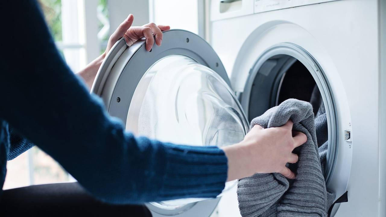 Auf dem Foto befüllt eine Frau eine Waschmaschine mit Wäsche.