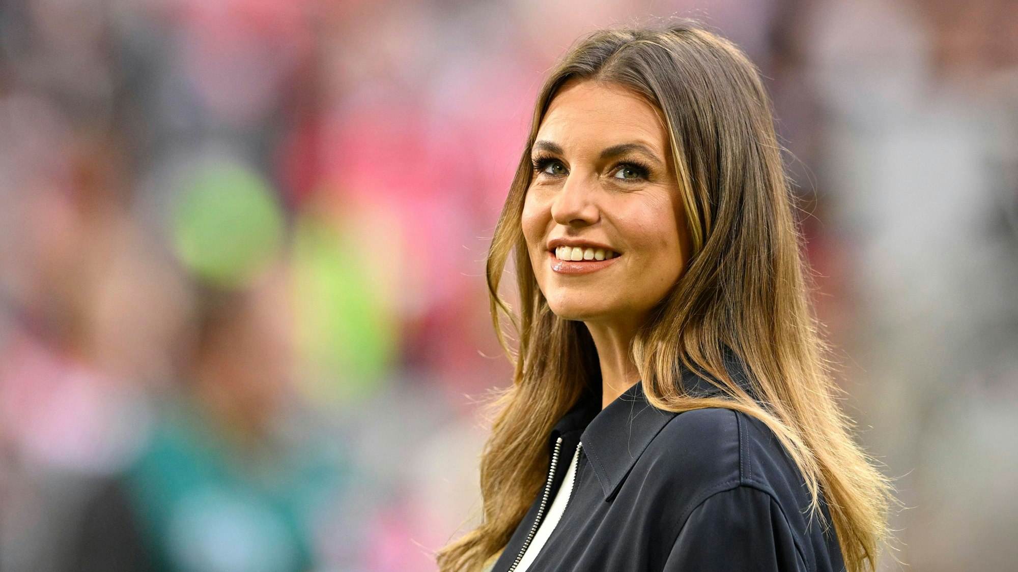 Laura Wontorra lächelt im Stadion vor einem Spiel.