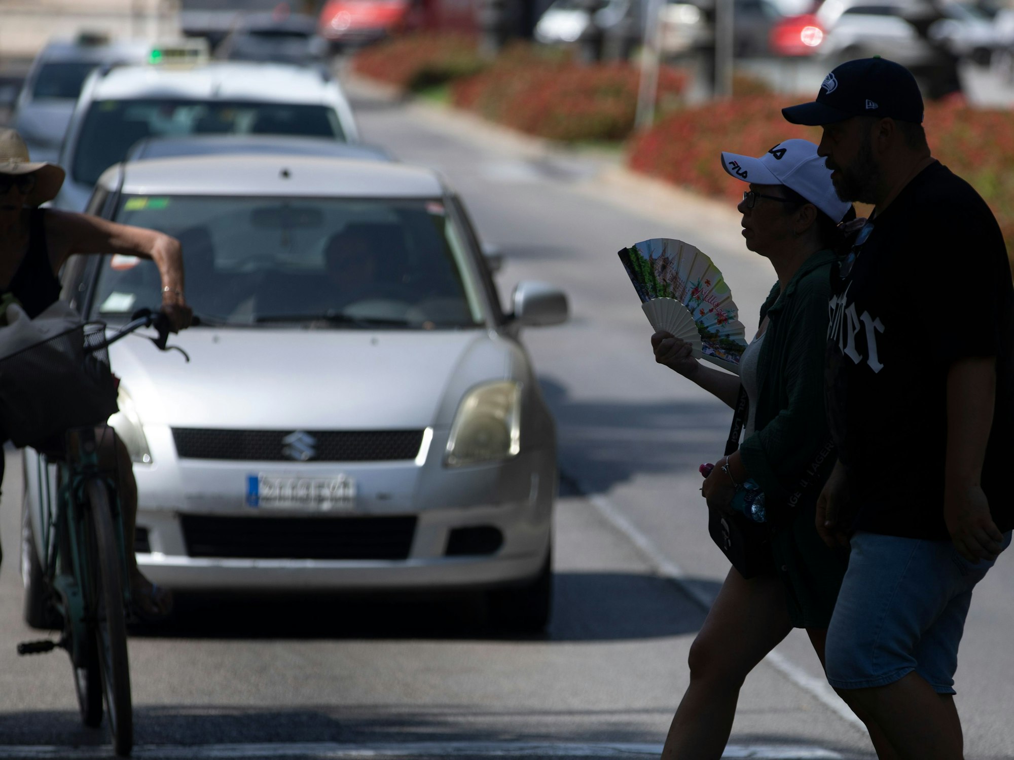 Eine Frau geht mit Fächer über eine Straße in der Innenstadt.