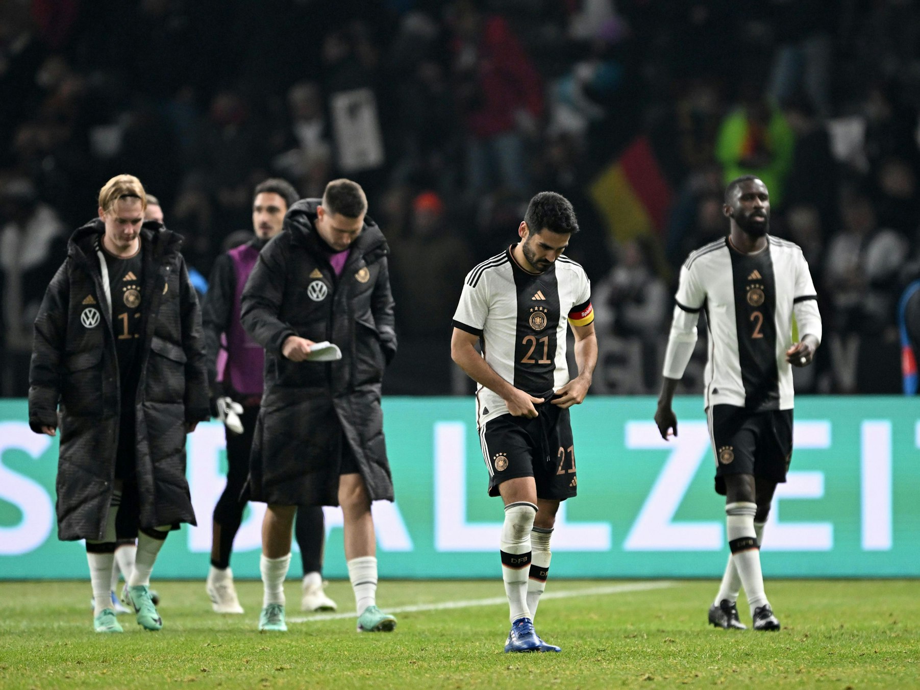 Antonio Rüdiger und Ilkay Gündogan, Niklas Süle, Mats Hummels und Julian Brand (v.r.) laufen mit hängenden Köpfen über den Platz.