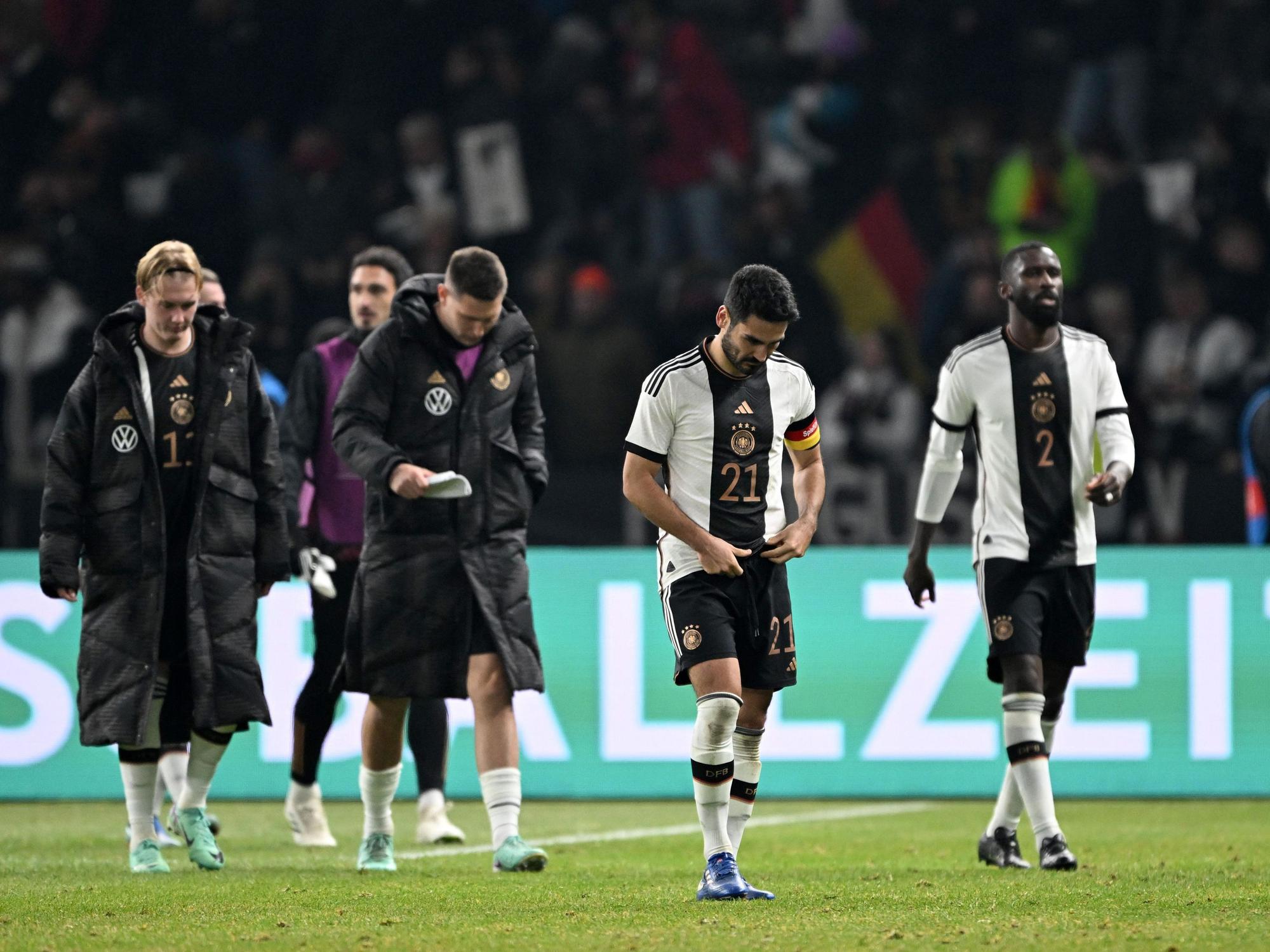 Antonio Rüdiger und Ilkay Gündogan, Niklas Süle, Mats Hummels und Julian Brand (v.r.) laufen mit hängenden Köpfen über den Platz.